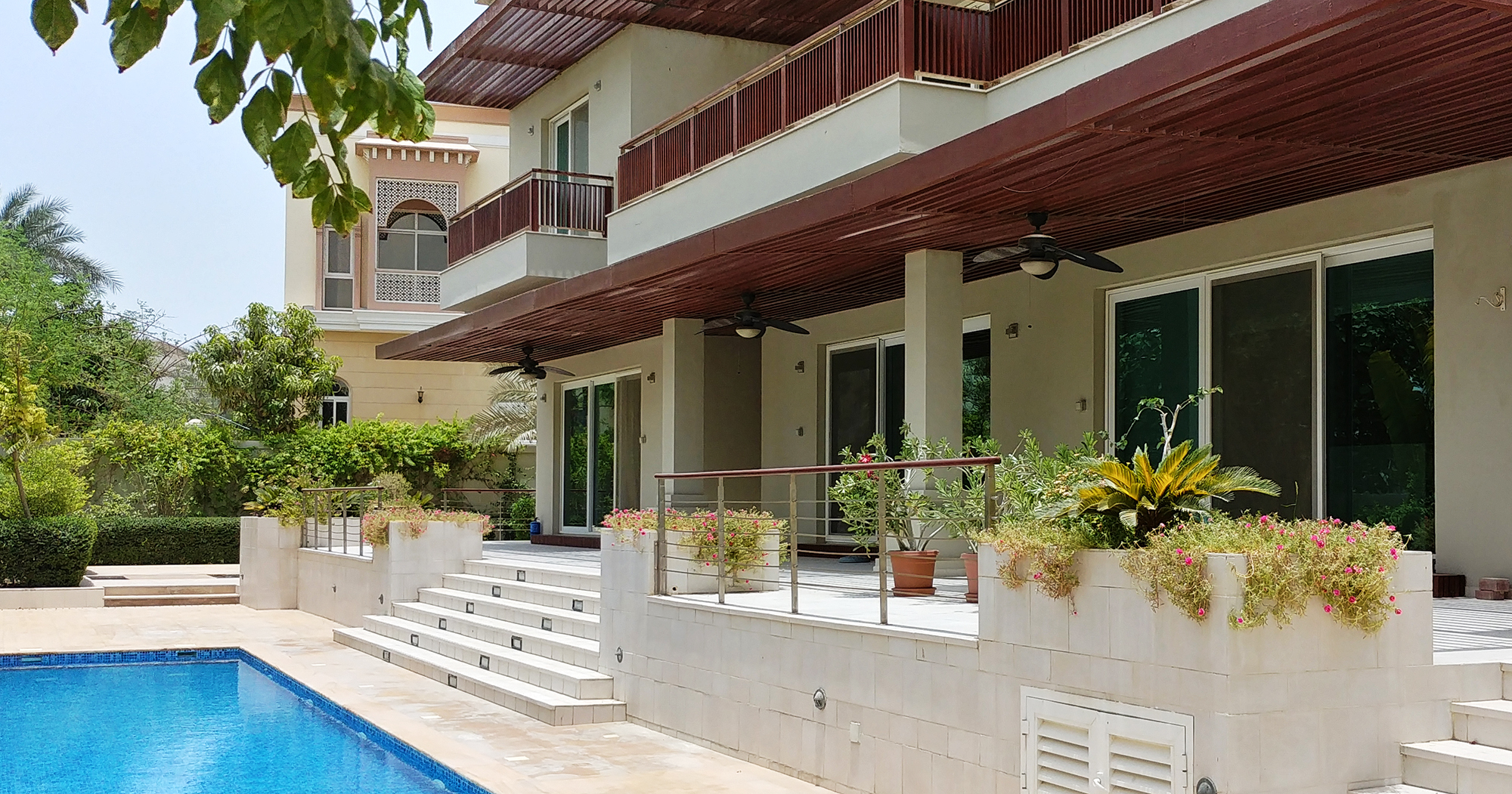 Wooden pergola shade the external dining terrace facing the pool at the Samina Ahmed Villa in Emirates Hills by RTAE